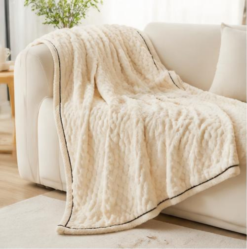 Plaid polaire blanc à bordure, posé en plein sur le canapé