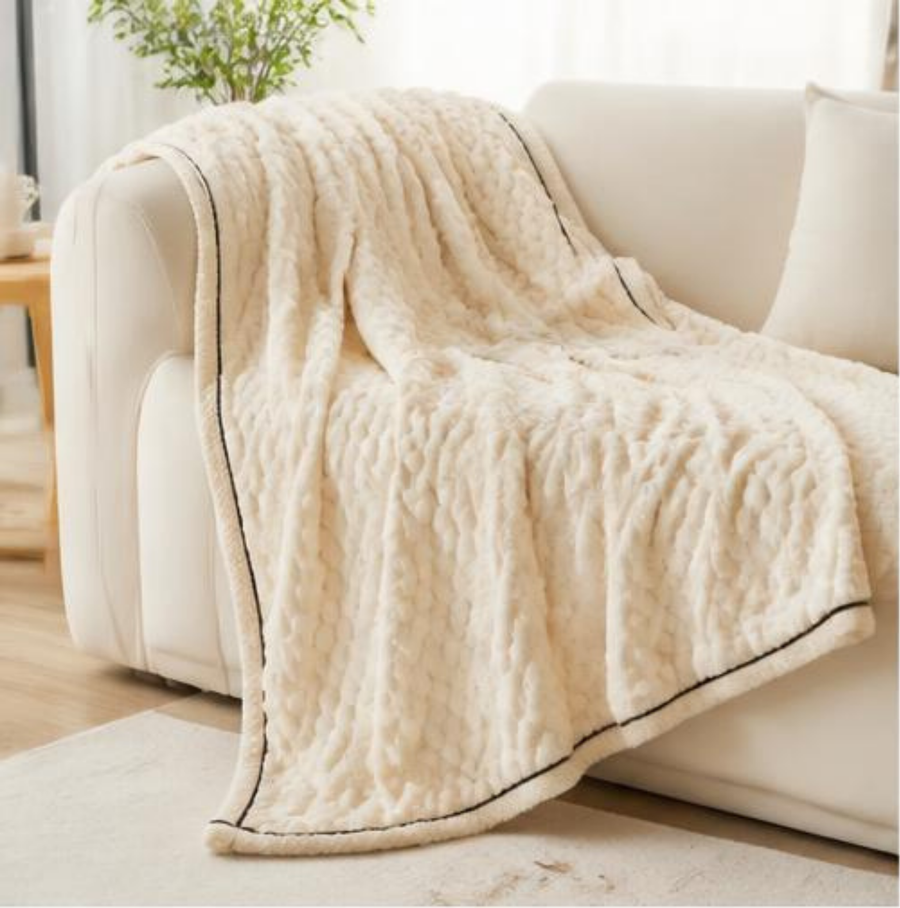 Plaid polaire blanc à bordure, posé en plein sur le canapé